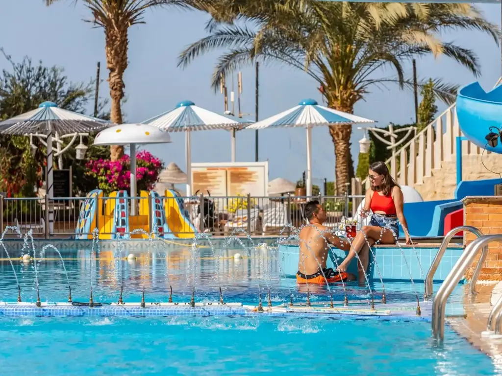 Гости почиват на ръба на басейна с детските пързалки – AMC Royal Hotel & Spa, Хургада