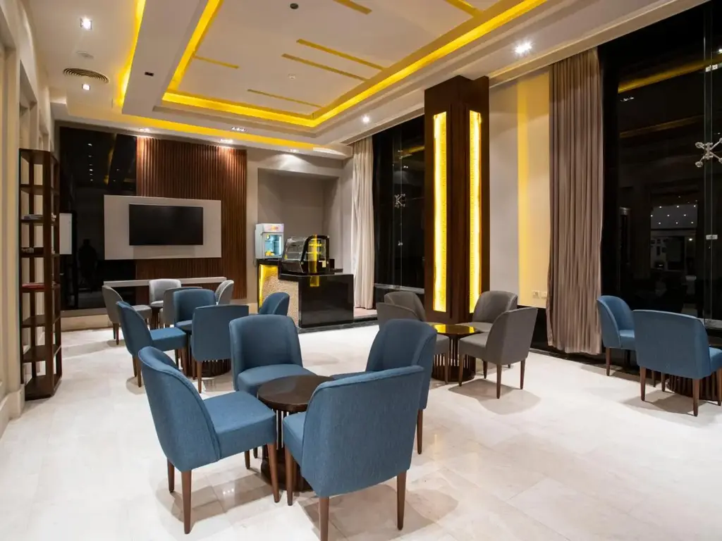 Сини кресла и високи прозорци в зоната за отдих на лобито – AMC Royal Hotel & Spa, Хургада