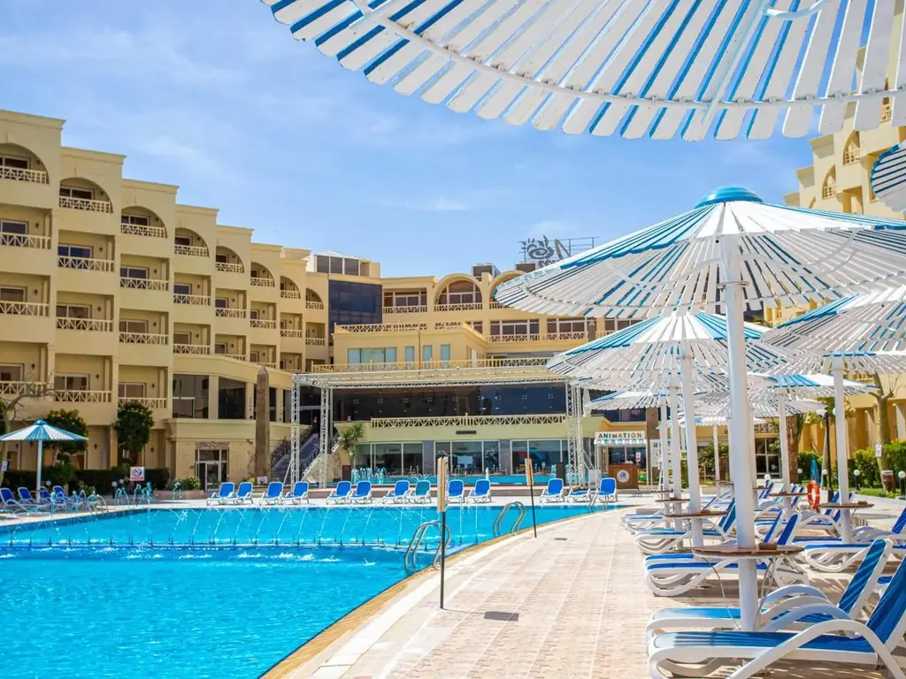 Басейн с шезлонги под бели чадъри пред сградите – AMC Royal Hotel & Spa, Хургада