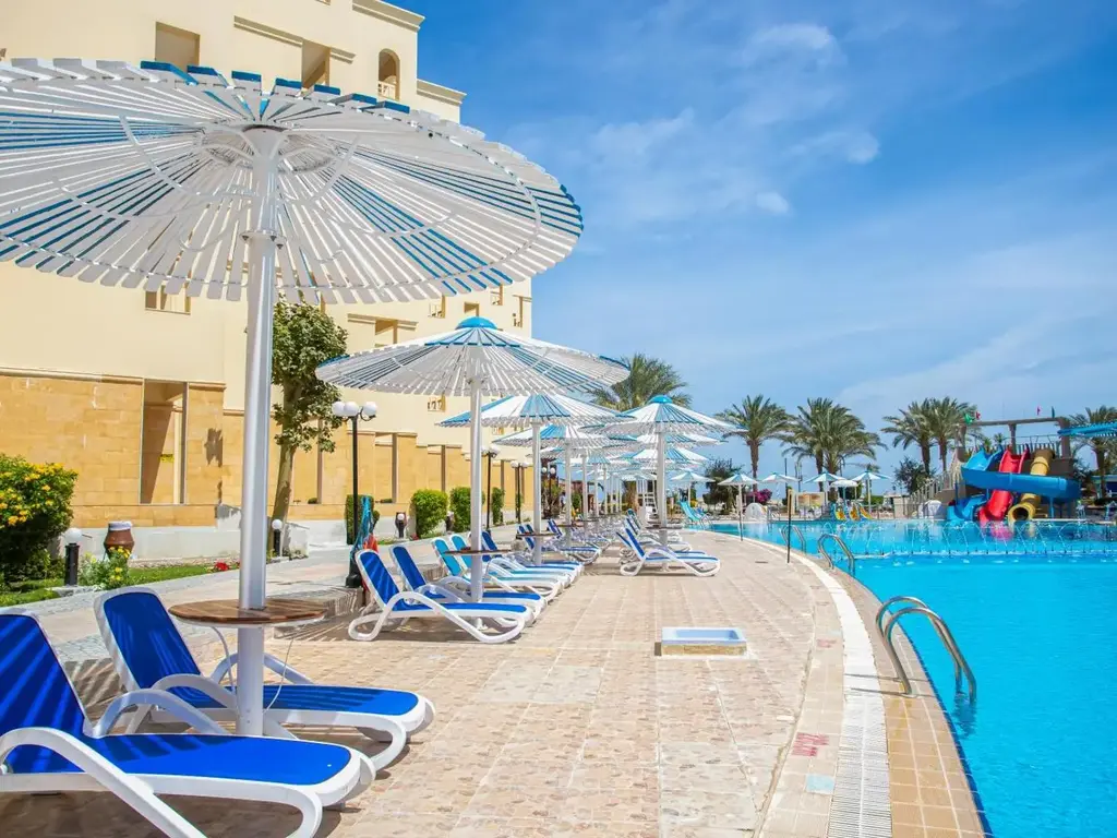 Басейн със сини шезлонги и раирани чадъри – AMC Royal Hotel & Spa, Хургада