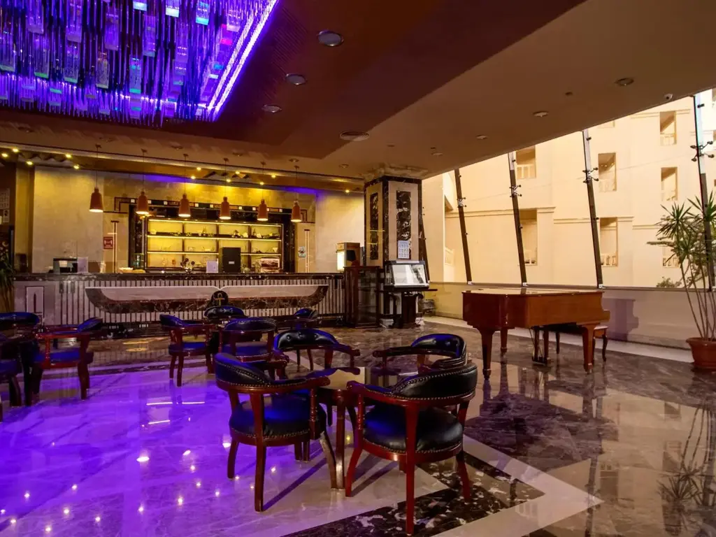 Бар с лилаво осветление на пода и тъмни кресла – AMC Royal Hotel & Spa, Хургада