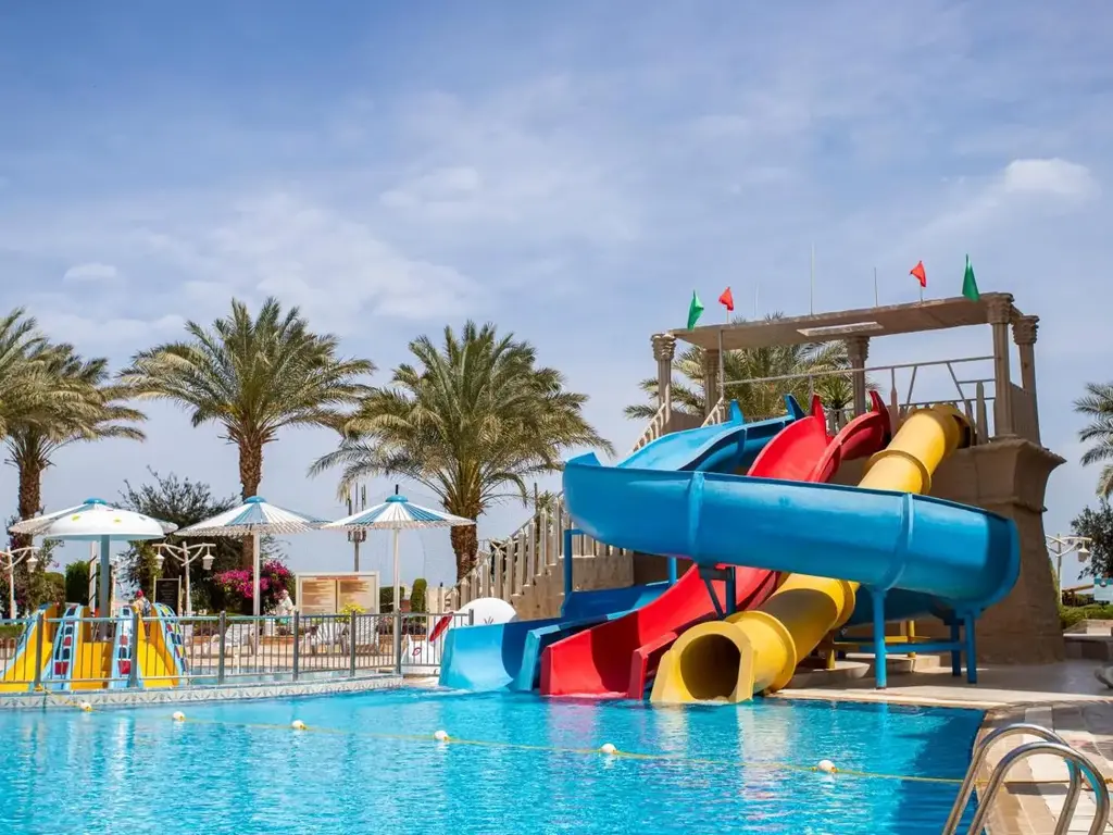 Цветни водни пързалки над басейна сред палмите – AMC Royal Hotel & Spa, Хургада