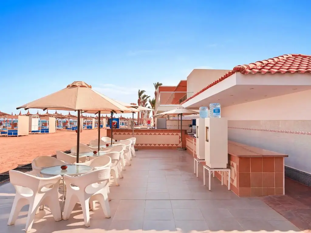 Тераса с чадър и бели столове – Pickalbatros Jungle Aqua Park Resort - Neverland Hurghada, Хургада