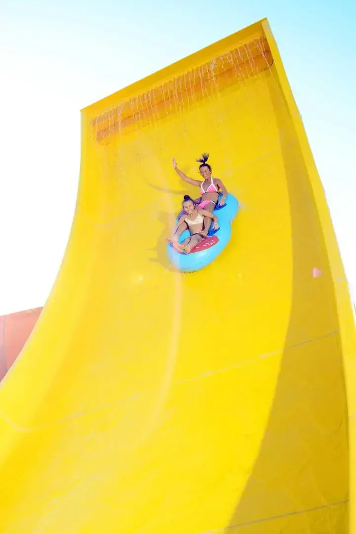 Деца се спускат с гума по жълта пързалка – Pickalbatros Jungle Aqua Park Resort - Neverland Hurghada, Хургада