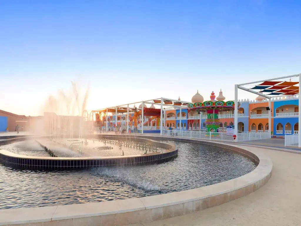 Фонтан и пъстри сгради на вечерна светлина – Pickalbatros Jungle Aqua Park Resort - Neverland Hurghada, Хургада