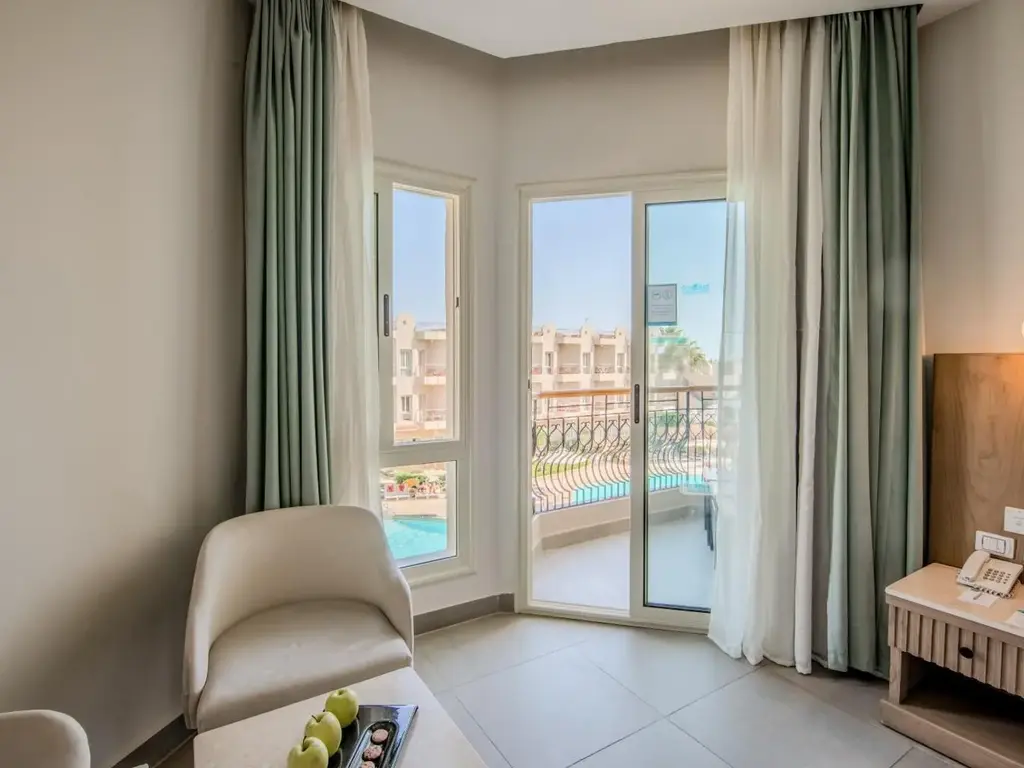 Фотьойл и стъклена врата към балкон с изглед към басейна – Sunrise Aqua Joy Resort, Хургада