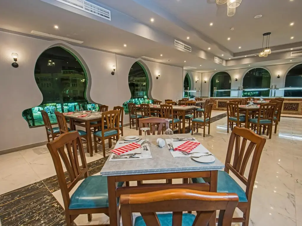 Зала на ресторанта с арковидни прозорци и тюркоазени столове – Sunrise Aqua Joy Resort, Хургада