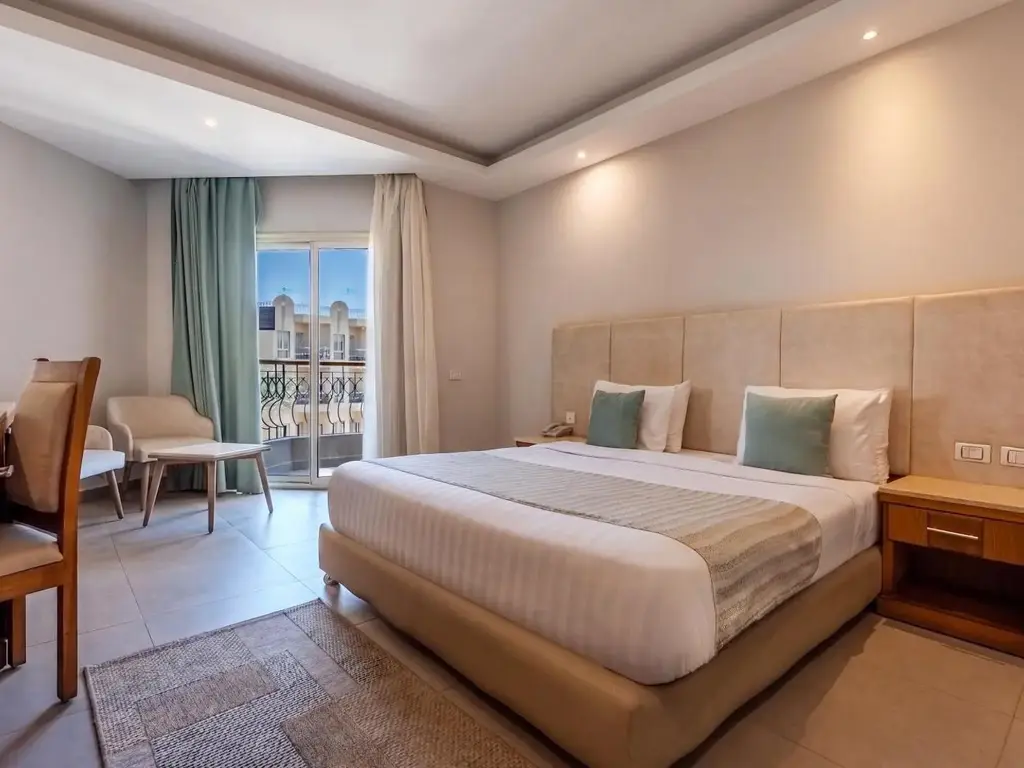 Двойно легло, стол и прозорец с изглед към сградите на комплекса – Sunrise Aqua Joy Resort, Хургада