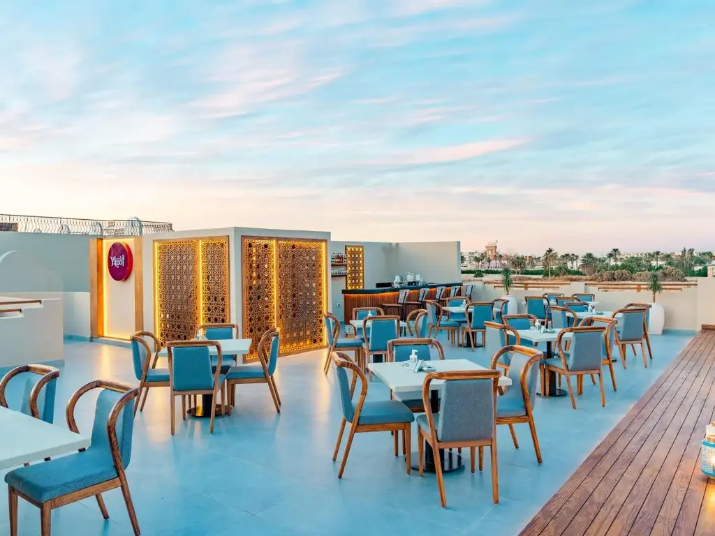 Покривна тераса с тюркоазени столове и дървени паравани по залез – Sunrise Aqua Joy Resort, Хургада