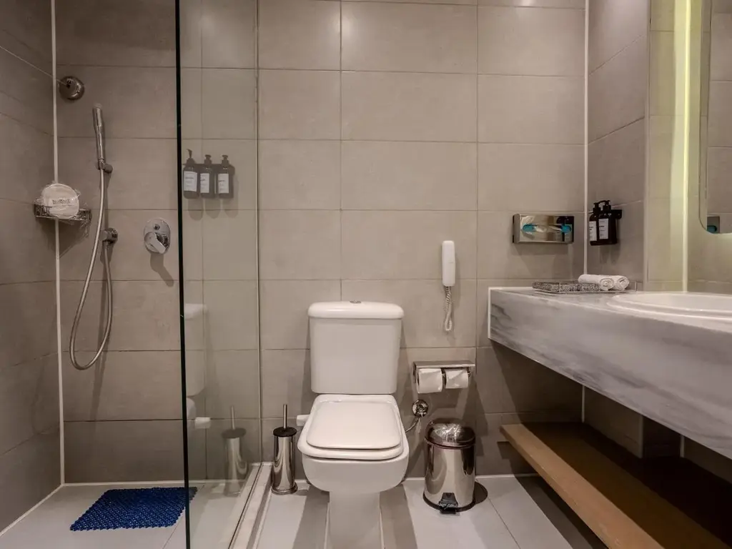 Сива баня с душ зад стъклена преграда, тоалетна и козметика – Sunrise Aqua Joy Resort, Хургада