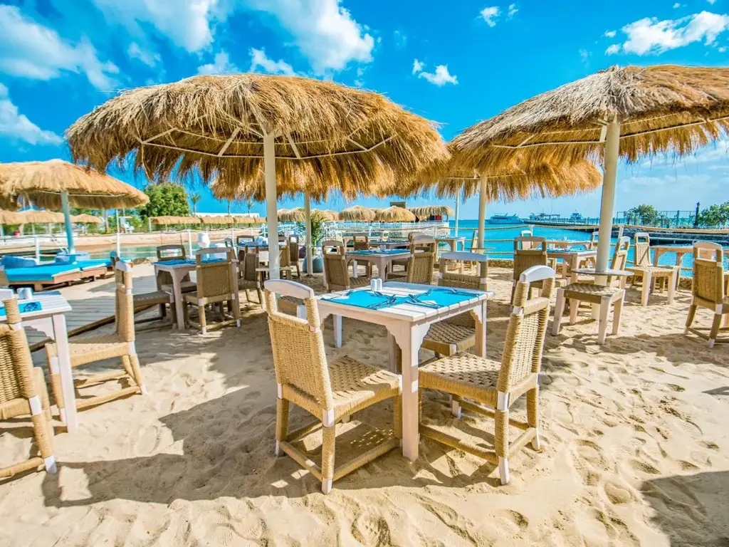 Ресторант на пясъка с маси и столове под сламени чадъри – Sunrise Aqua Joy Resort, Хургада