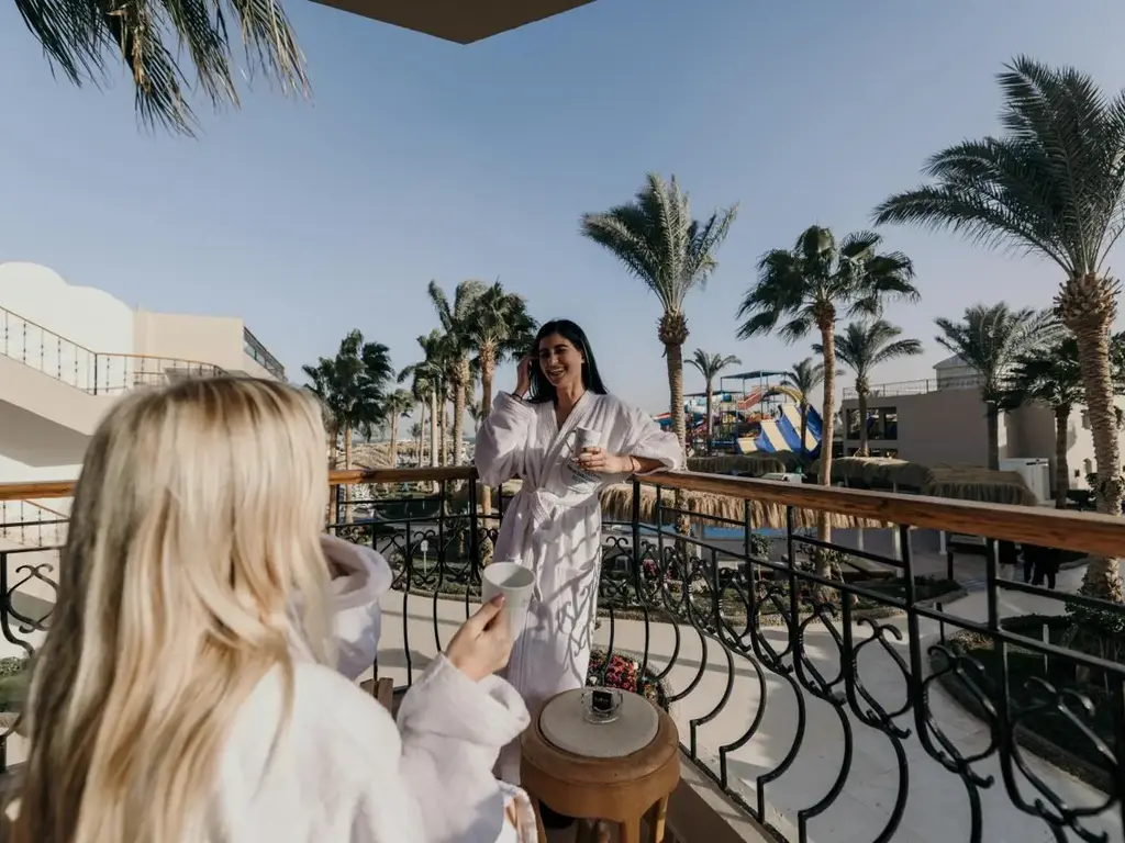 Гостенки на балкон с ажурен парапет и изглед към палмите – Sunrise Aqua Joy Resort, Хургада