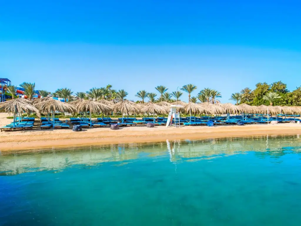 Пясъчен плаж със сламени чадъри и тюркоазена вода в лагуната – Sunrise Aqua Joy Resort, Хургада