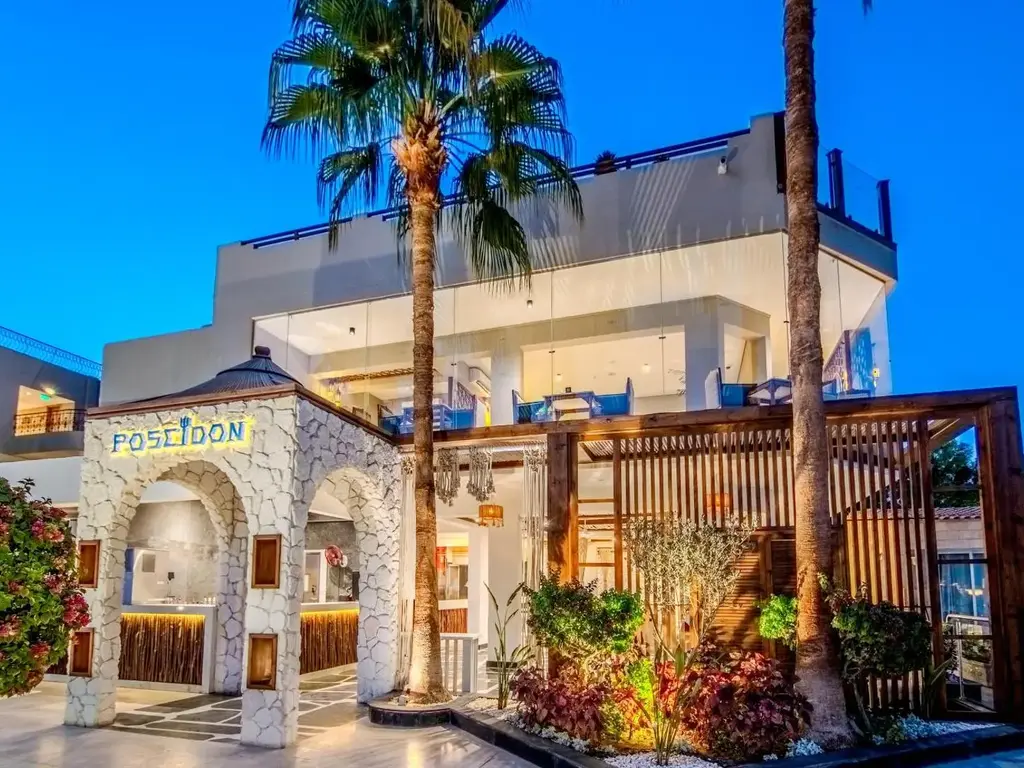 Вход на гръцкия ресторант Poseidon с бяла арка и палми вечер – Sunrise Aqua Joy Resort, Хургада