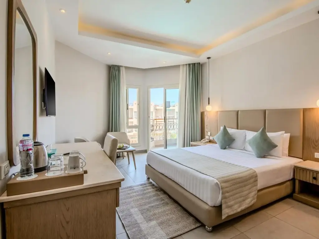 Стая с двойно легло, бюро и врата към балкона със зелени завеси – Sunrise Aqua Joy Resort, Хургада