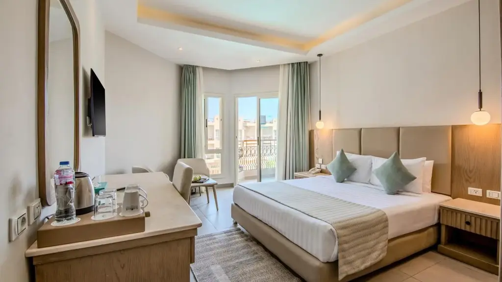 Стая с двойно легло, бюро и врата към балкона със зелени завеси – Sunrise Aqua Joy Resort, Хургада